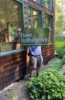 Man holding a sign that says Dave Upthegrove